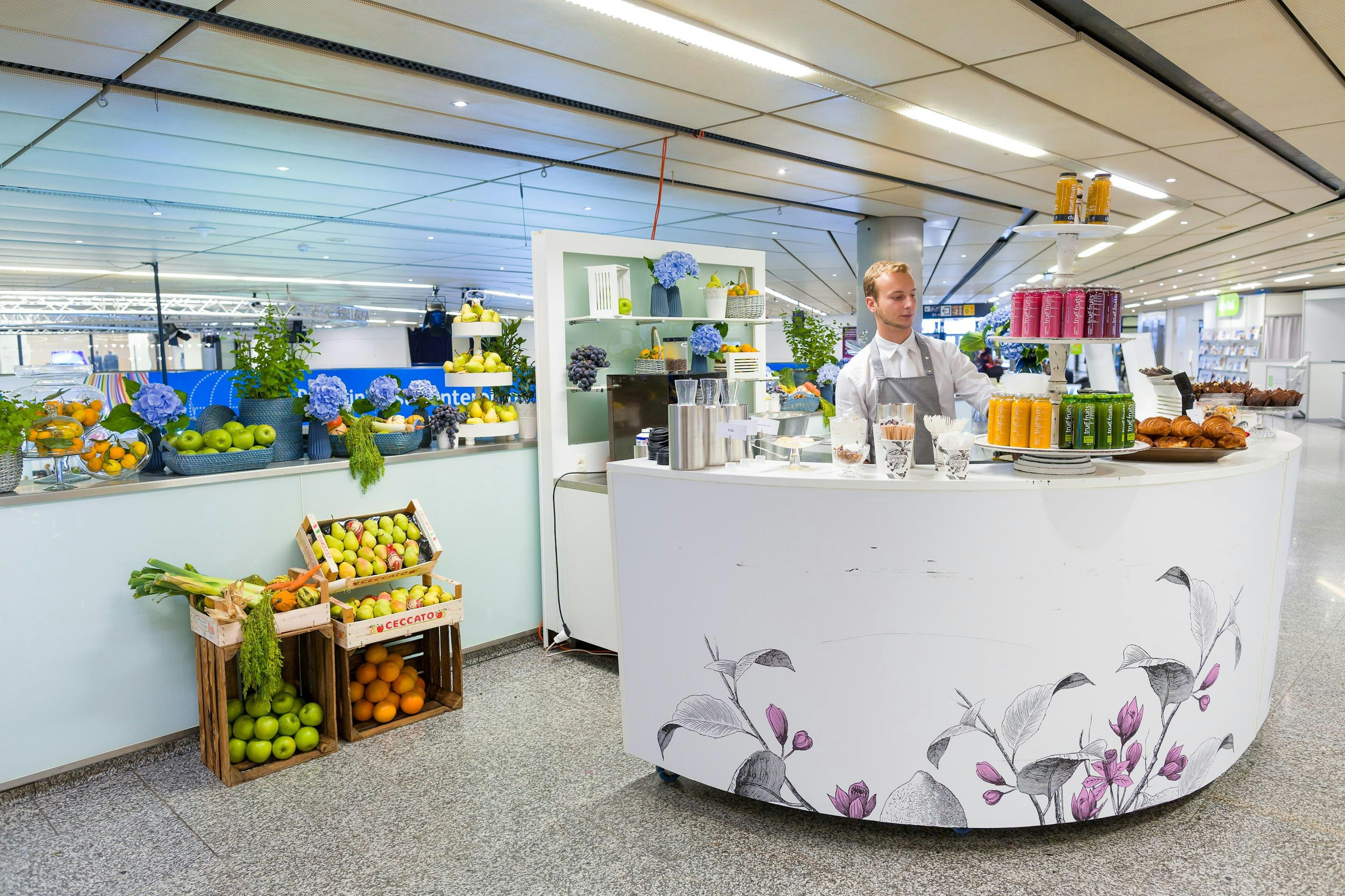 Foto: weiße Bar mit Kellner und Obstkisten in einer weißen Halle