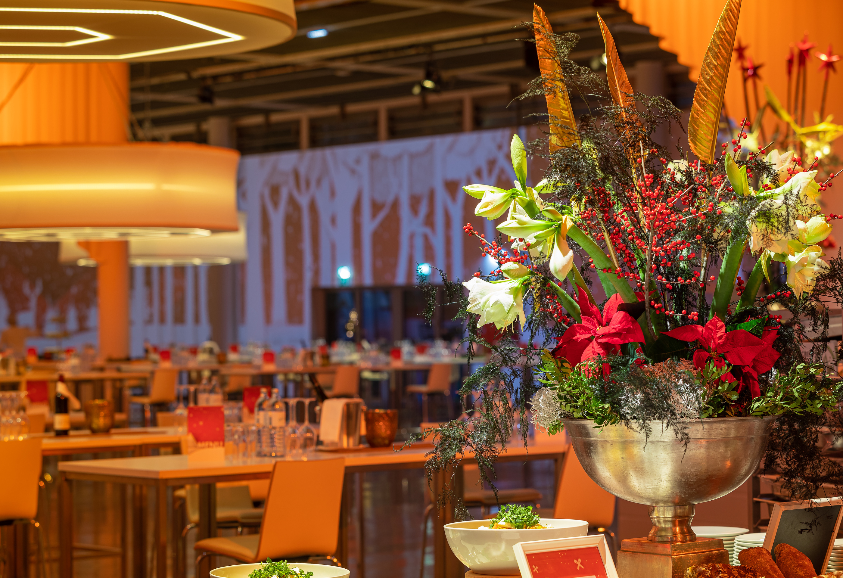 Foto: Eine Halle mit Blumengesteck, gedeckten Tischen, Lampen und Wandprojektion