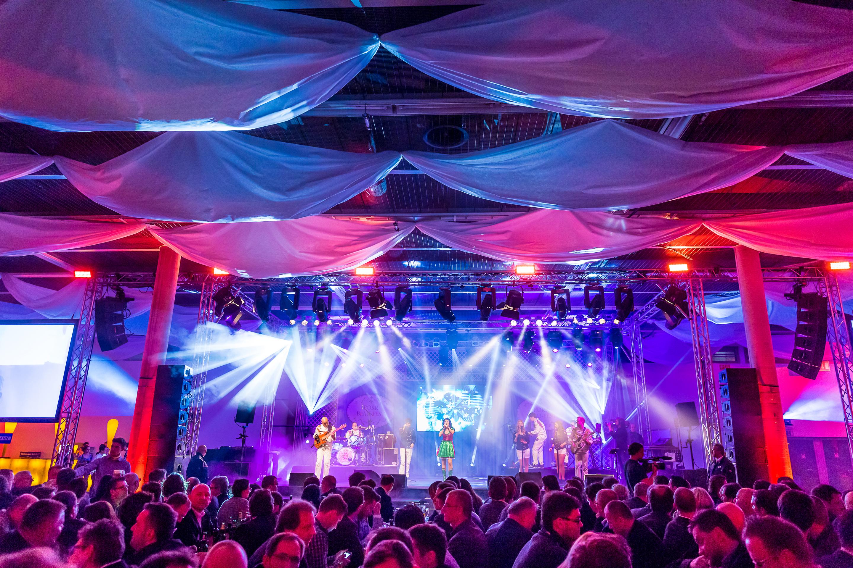Foto: Halle im rot-blauen Licht mit Menschen bei einem Konzert