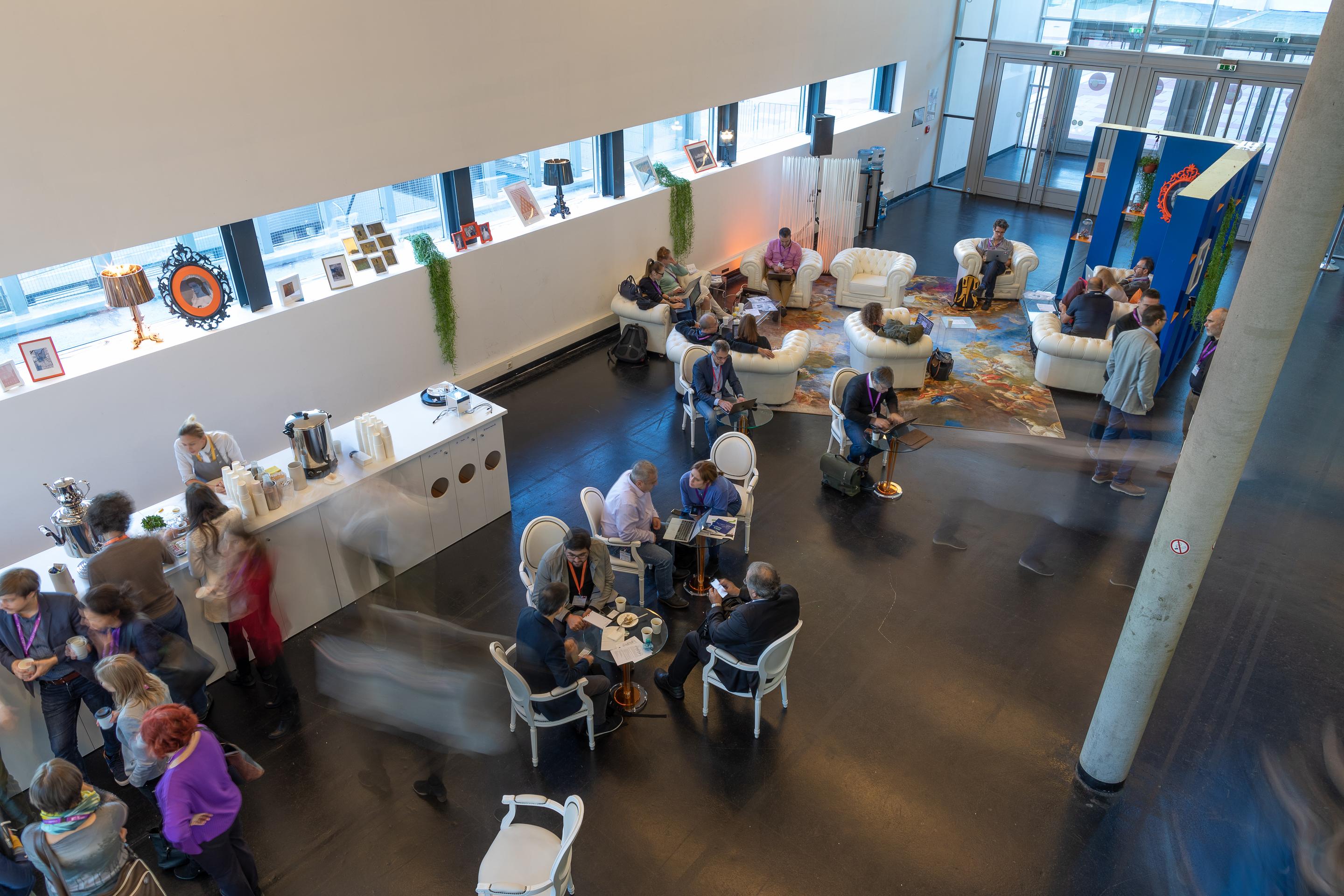 Foto: Cafebar und Menschen in Sitzgruppen in einer Halle