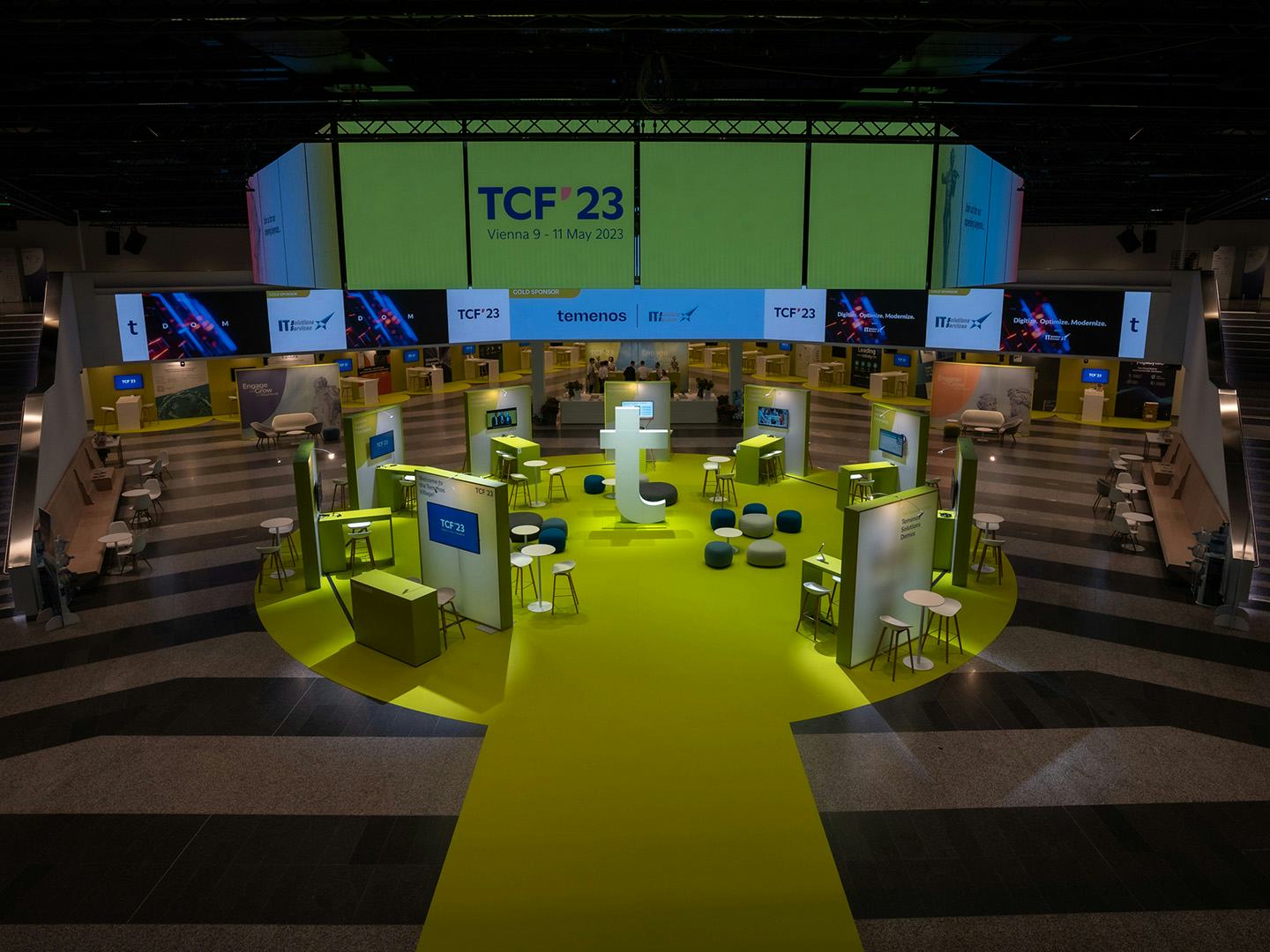 Foto: Dunkler Raum mit gelben Teppich, Networking-Bereichen und beleuchteten LED-Flaechen