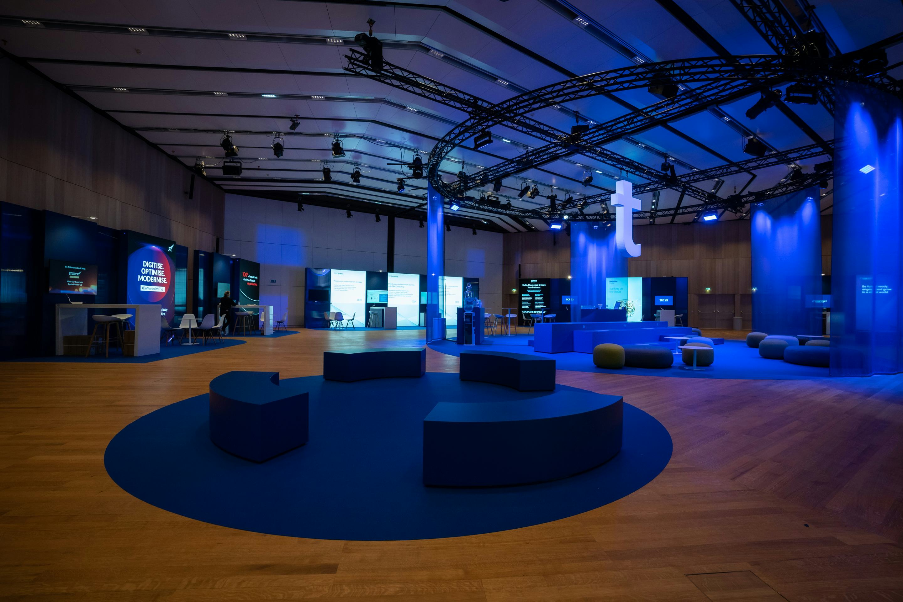 Foto: Raum mit blauen Vorhaengen, Networking-Bereichen und beleuchteten Screens