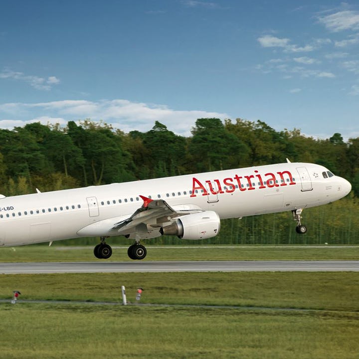 Foto: weisses Flugzeug mit roter Aufschrit "Austrian" startet an der Startbahn
