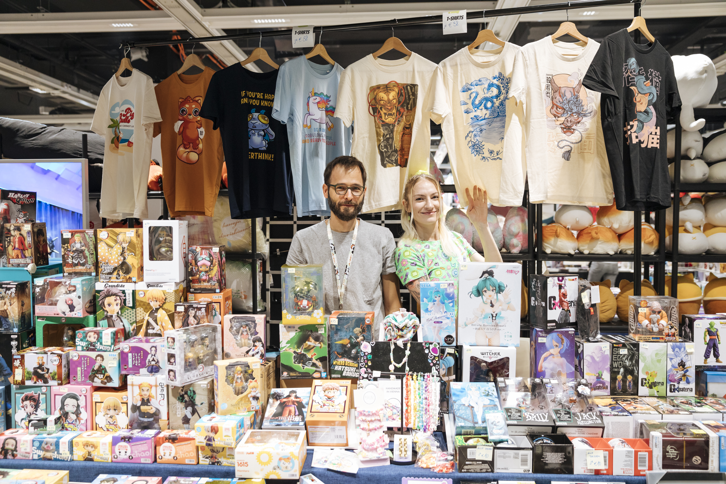 Foto: junger Mann und Frau hinter einem Verkaufsstand mit Manga Produkten