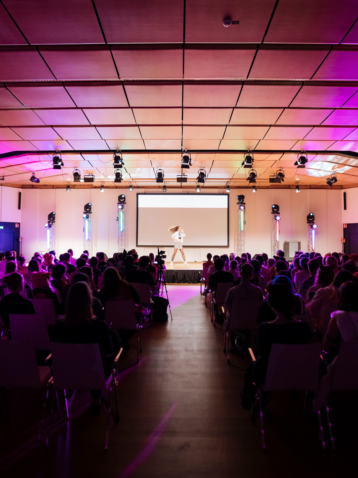 Foto: Saal mit vielen Menschen und einer Taenzerin auf einer Buehne