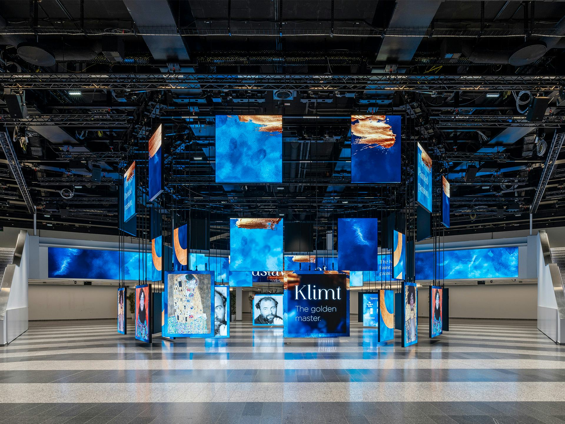 Foto: blaue beleuchtete Paneele mit Klimt Bildern in einer Halle