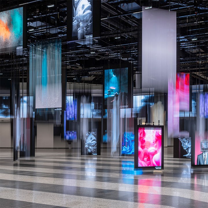 Die Eingangshalle des Austria Center Vienna mit beleuchteter polySTAGE LED-Installation, die Fotos und Kunstwerke zeigt.